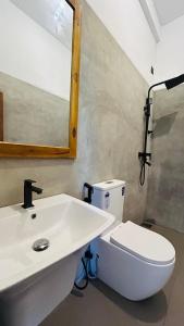 a bathroom with a white sink and a toilet at Saffron Swell Villa in Arugam Bay