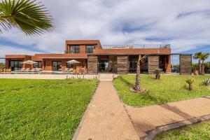 a brick house with a palm tree in front of it at Citrus Bloom Manor Marrakech in Oulad Mazoug