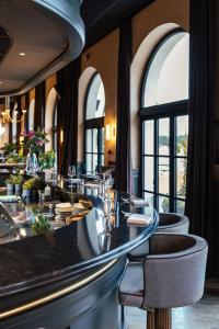 a restaurant with a bar with chairs and windows at Jadran Heritage Hotel, Valamar Collection in Poreč