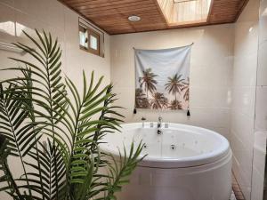 a bath tub in a bathroom with a palm tree picture at Gapyeong Sol Stay Spa Pension in Gapyeong