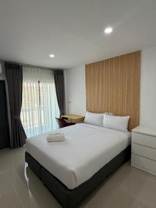 a bedroom with a large white bed and a desk at I am Daily Mansion in Ban Phan Sadet Nai