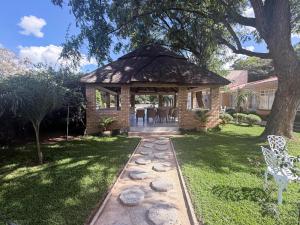 a gazebo with a table and chairs in a yard at Mevis Boutique Hotel in Bulawayo
