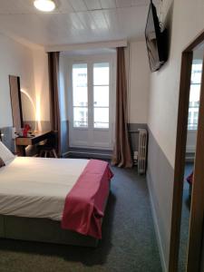 a hotel room with a bed and two windows at Hôtel Saint Daniel in Nantes