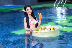 a woman in a swimming pool with a cake in the water at TTC Hotel Michelia in Nha Trang
