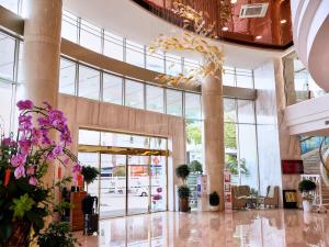 a lobby with a large building with glass doors and flowers at TTC Hotel Michelia in Nha Trang