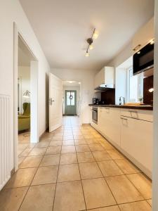 a kitchen with white cabinets and a tile floor at Haus Charlotte mit Meerblick in Fehmarn