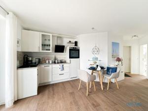 a kitchen with white cabinets and a table and chairs at Marina Liebe in Cuxhaven