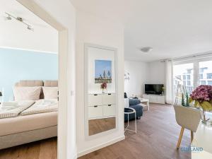 a white living room with a couch and a mirror at Marina Liebe in Cuxhaven