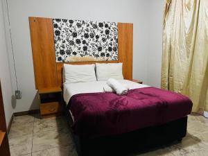 a bedroom with a bed with a purple blanket at Lodge & Backpackers at Star Legend Parow in Parow