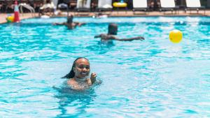 a woman playing with a ball in a swimming pool at Ridge Cabin Resort in Nairobi