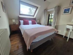 a bedroom with a bed with red pillows and a window at The Old Coach House in Pitlochry