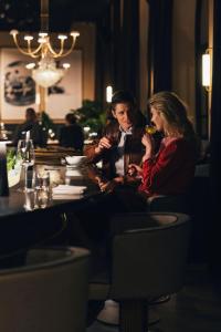 a man and woman sitting at a table drinking wine at Jadran Heritage Hotel, Valamar Collection in Poreč