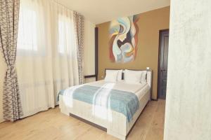a bedroom with a bed and a painting on the wall at Pensiunea Dezire in Baile Unu Mai +35 photos