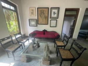 a living room with a red couch and chairs at Weaver Bird Residencies in Hewagama