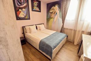 a bedroom with a bed and paintings on the wall at Pensiunea Dezire in Baile Unu Mai