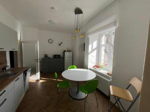 a kitchen with a white table and green chairs at Apartmán Na Valešince in Příbram