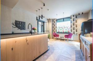 a kitchen with a sink and a counter with pink chairs at Hôtel Le Cor de Chasse in Saint-Hubert