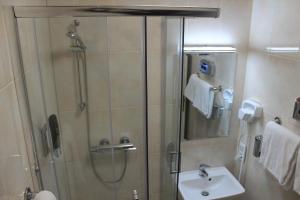 a shower with a glass door next to a sink and a mirror at Fair Hotel Europaallee in Frankfurt