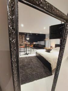 ein Spiegel, der ein Schlafzimmer mit einem Bett und einem Tisch widerspiegelt in der Unterkunft Le sandron in Marchin