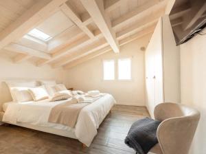 a bedroom with a large white bed and a chair at PENTHOUSE ISEO LAKE VIEW - Free Wi-Fi and Private Parking Included in Sale Marasino