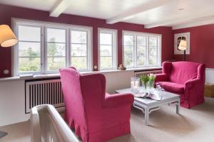 a living room with two pink chairs and a table at Haus Peacock in Kampen