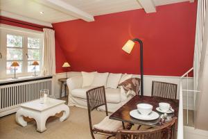 a living room with red walls and a table and chairs at Haus Peacock in Kampen
