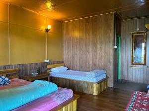 two beds in a room with wooden walls at Soshing Homestay in Ravangla +34 photos