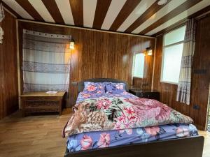 a bedroom with a bed in a room with wooden walls at Soshing Homestay in Ravangla