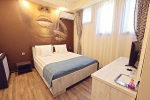 a hotel room with a bed with a painting on the wall at Pensiunea Dezire in Baile Unu Mai
