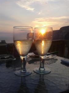 dos copas de vino sentadas en una mesa con la puesta de sol en Palm Court Apartment, en Xlendi