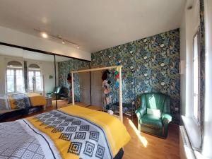 a bedroom with a bed and a green chair at Cocorico in Boué