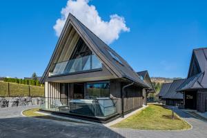 a house with a gambrel roof on a street at Crystal Peak Villas z prywatnym jacuzzi, Odkryj-Zakopane in Kościelisko
