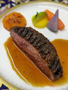 a piece of meat with sauce on a plate with fruit at ル カフェ プランタニエ in Yokote +2 photos