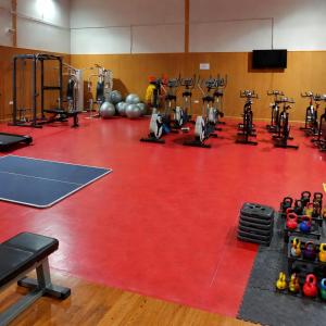 a gym with a red gym floor with machines at Albergue la Fontanina ALCC00043 in Mata de Alcántara