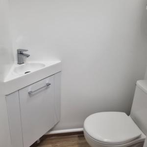 a white bathroom with a toilet and a sink at Résidences Eska in Bobigny +8 photos