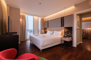 a bedroom with a large white bed and a television at Savhotel Mantegna Padova in Padova