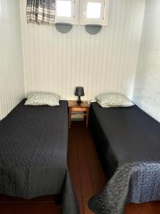 two beds in a room with a table and two windows at Vuohensaari, Rantatalo 5 in Salo