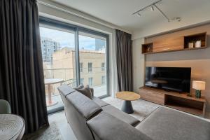 a living room with a couch and a large window at Mercury Suites Premium Apartments With Pool Access in St. Julianʼs