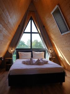 a bed in a room with a large window at Vino Chalets Bran in Sohodol