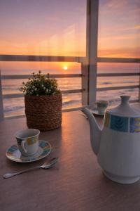 a tea pot and cups on a table with a view of the ocean at Un Rincon en el Mar in Bellreguart