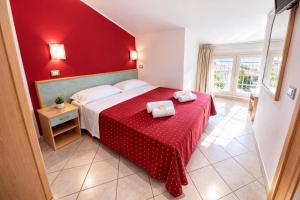 a red bedroom with a bed with a red wall at Hotel Villa Tina Easy Stay B&B in Cesenatico