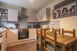 a kitchen with a wooden table and a kitchen with white cabinets at Boar Edge Cottage in Richmond