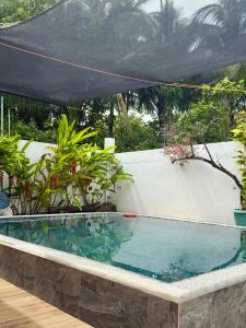 a swimming pool with a black canopy over it at Thani's Little Cabin Rental - Native Room in Caibiran