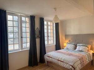 a bedroom with a bed and two windows at Le 8 Chaussée Honfleur in Honfleur