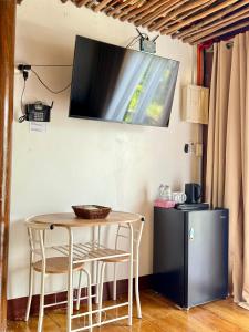 a table and chairs with a television on the wall at Thani's Little Cabin Rental - Native Room in Caibiran