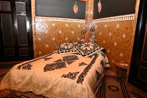 a bedroom with a bed with a black and white comforter at Dar Maya Original Suite & Spa in Fez