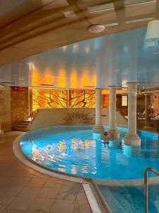 ein großes Schwimmbecken in einem Gebäude mit Säulen in der Unterkunft Meduza Hotel & Spa in Mielno