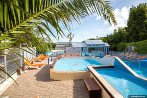 a large swimming pool with chairs and a building at Camping Bel Air - Cancale in Cancale