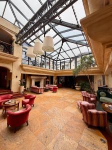 eine große Lobby mit Glasdecke und roten Stühlen in der Unterkunft Meduza Hotel & Spa in Mielno