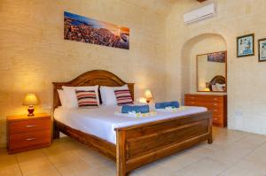 a bedroom with a large bed and a mirror at Il-Kampnar Gozo Farmhouse with Private Pool in Sannat +33 photos